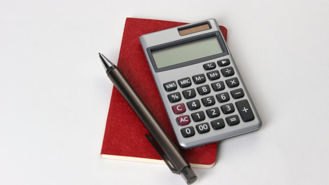 Taschenrechner und Stift auf rotem Notizbuch