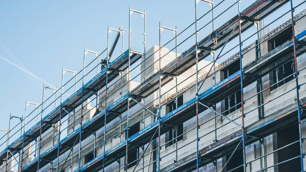 Hausfassade mit Gerüst, an der Wand helle Dämmplatten