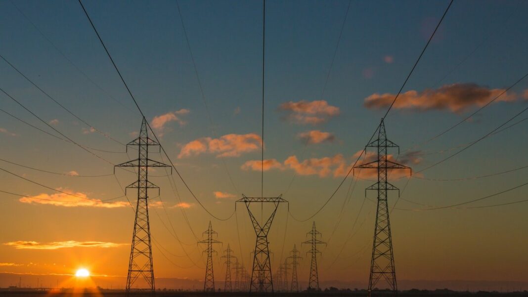 Strommasten mit Hochspannungsleitungen vor einem Sonnenuntergang